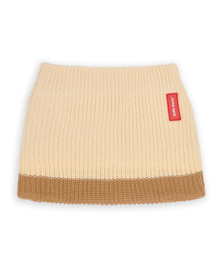 Gebreide Cocoon Sandy nekwarmer van Hello Hossy in lichtbeige met een bruine onderrand en rood merklabel.