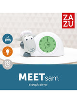 Grijze Zazu slaaptrainer Sam met open ogen en groene wijzerplaat op een witte tafel.