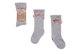 Lichtgrijze Clara kniekousen van Mama's Feet met roze strikjes en golvende boord, los en met verpakking.