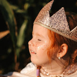Kind met een glinsterende kroon en Star Dust Rainbow gezichtsglitter in verschillende kleuren op de wang.