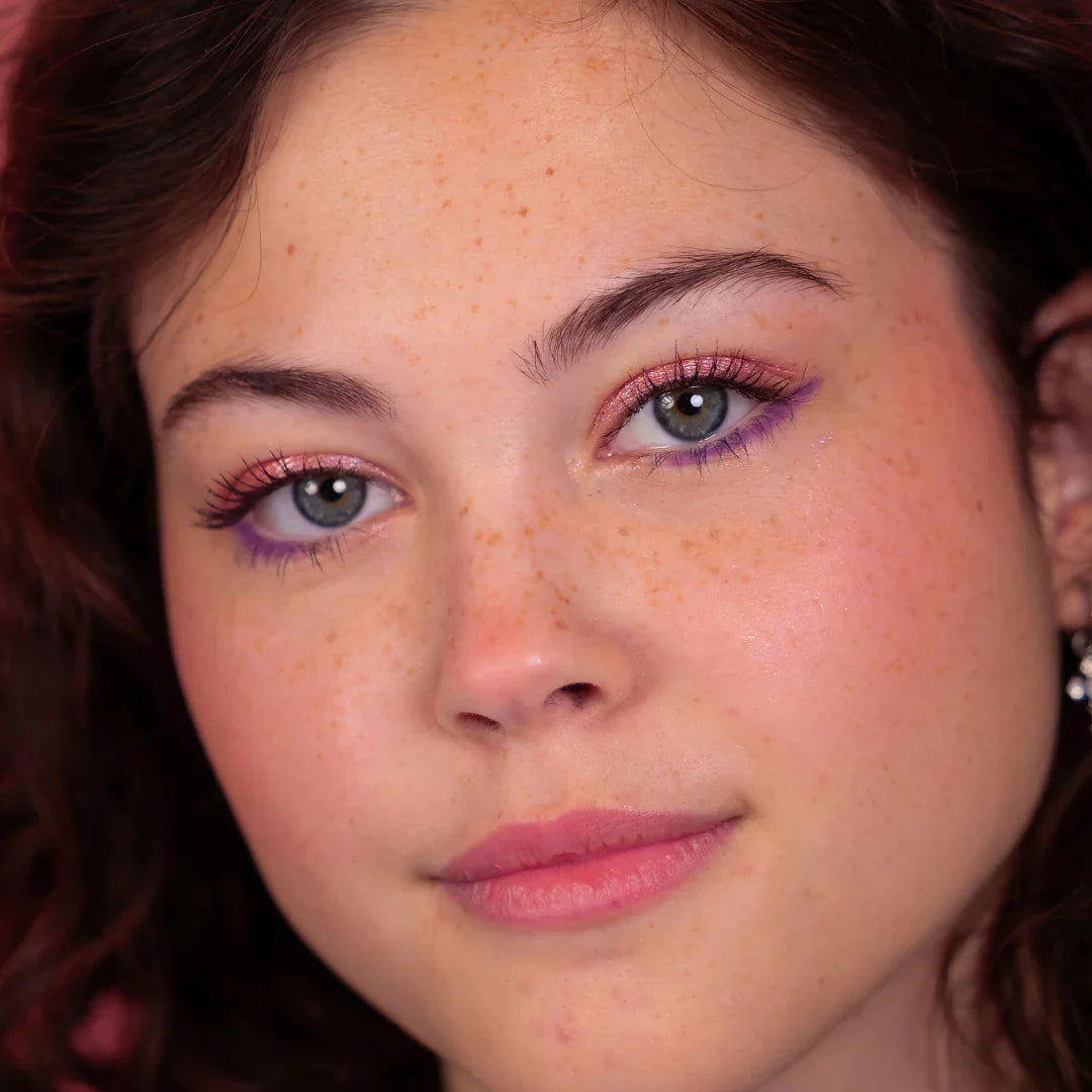 Model met glanzende roze oogschaduw en paarse eyeliner, met de Stardust Topper Camille op de oogleden.