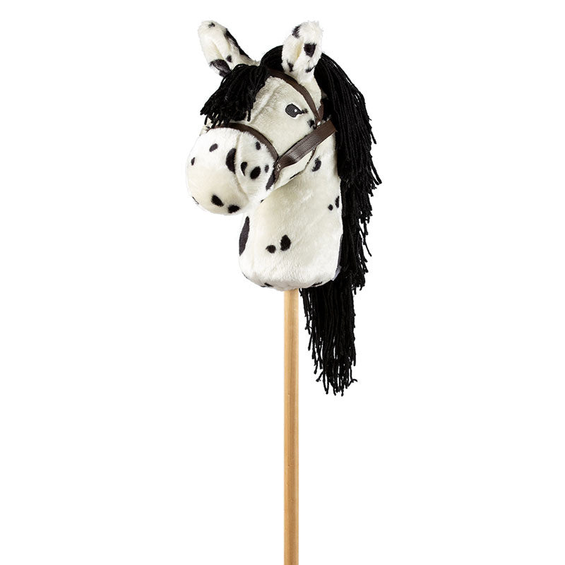 Wit stokpaardje met zwarte stippen, lange zwarte manen en een bruin hoofdstel, schuin van voren gezien.