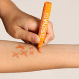 Hand tekent oranje kruisjes op een onderarm met de oranje tattoopen