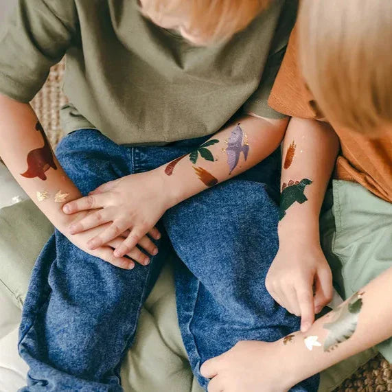 Kinderen met kleurrijke afwasbare dinosaurus-tatoeages op hun armen.