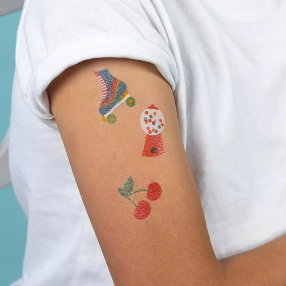Tijdelijke Top Banana kindertattoos van een rolschaats, kauwgomballenautomaat en kersen op een bovenarm