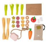 Voederset voor een stokpaard, uitgestald met appel, wortel, stro, groene stengels, snoepjes, voerzakje en roze liksteen.